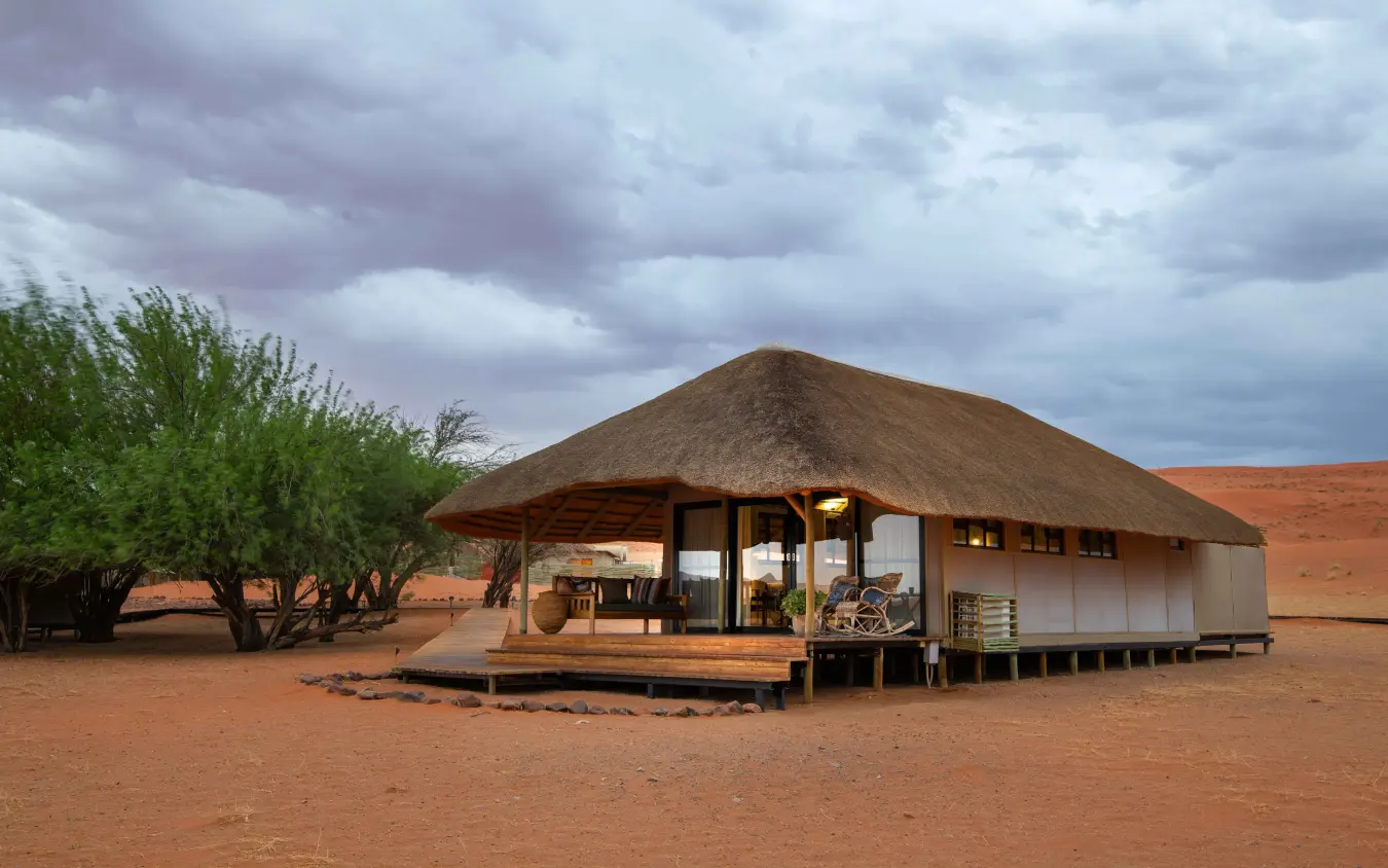 Luxury safari lodge with thatched roof on red earth plains, Kwessi Dunes, NamibRand Private Reserve, Namibia