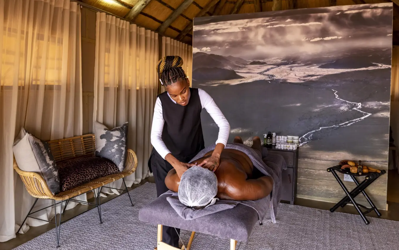 Spa therapist giving head massage in luxury lodge room with landscape view, Kwessi Dunes, NamibRand Private Reserve, Namibia