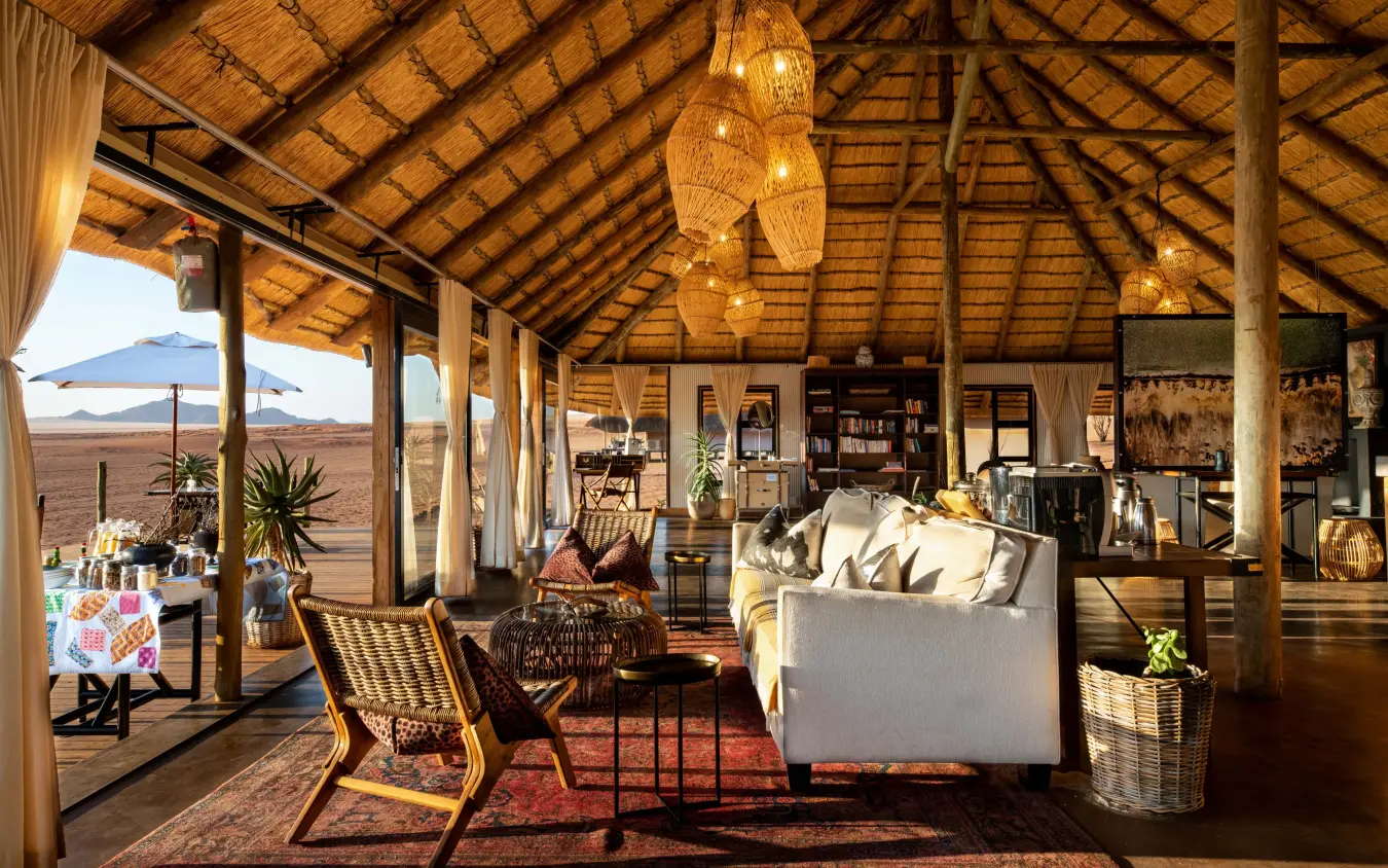 Open-sided lodge interior with lounge seating overlooking vast grassland plain, Kwessi Dunes, NamibRand Private Reserve, Namibia