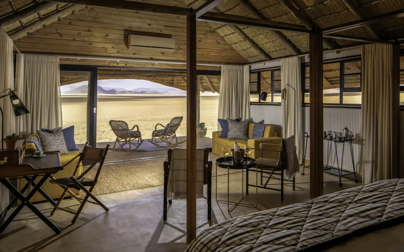 Luxury safari lodge interior with open-air deck overlooking expansive grassland valley, Kwessi Dunes, NamibRand Private Reserve, Namibia