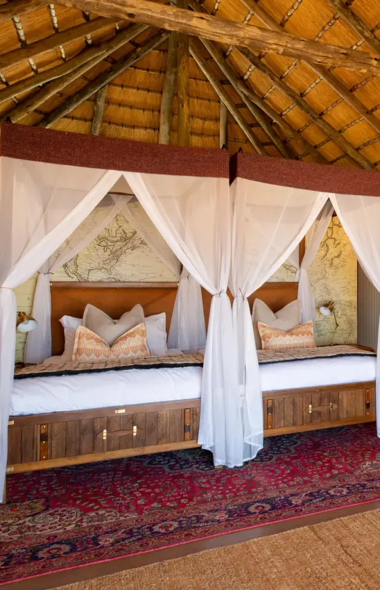 Luxury safari lodge bedroom with four-poster beds and thatched roof interior, Kwessi Dunes, NamibRand Private Reserve, Namibia