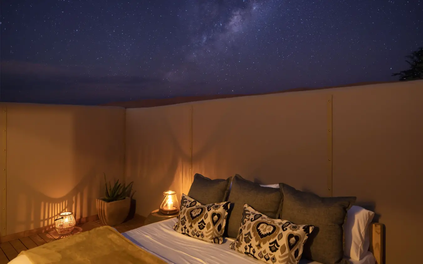 Luxury outdoor bedroom with starry night sky and Milky Way visible overhead, Kwessi Dunes, NamibRand Private Reserve, Namibia