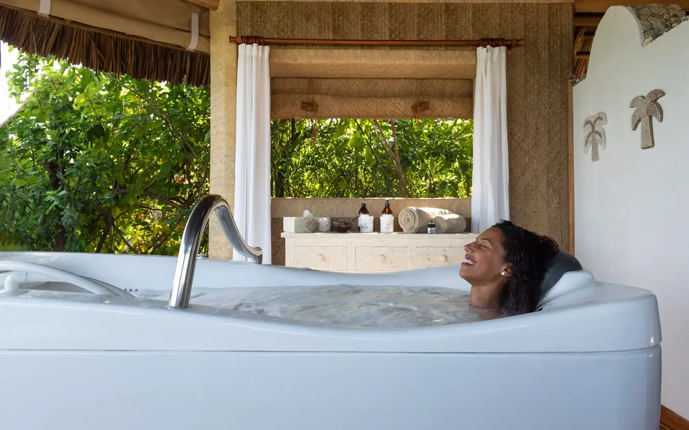 Woman relaxing in outdoor spa tub with lush garden views, Laba Fanjove, Zanzibar & Pemba, Tanzania