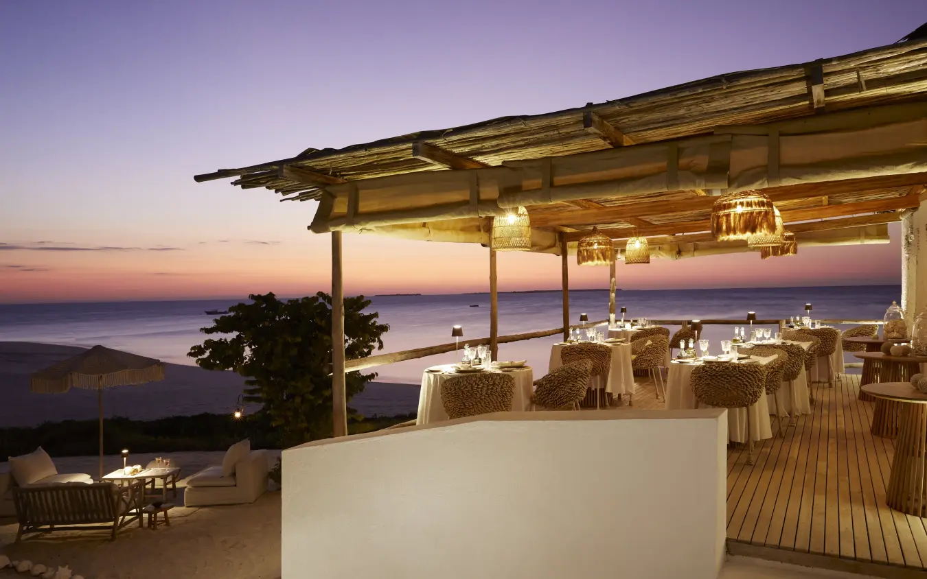 Beachfront terrace with dining tables at sunset overlooking coastal waters, Laba Fanjove, Zanzibar & Pemba, Tanzania