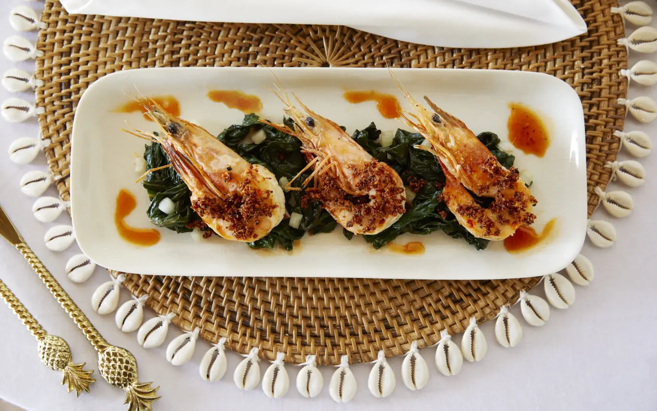 Plated seared prawns with greens and sauce garnish on woven placemat, Laba Fanjove, Zanzibar & Pemba, Tanzania