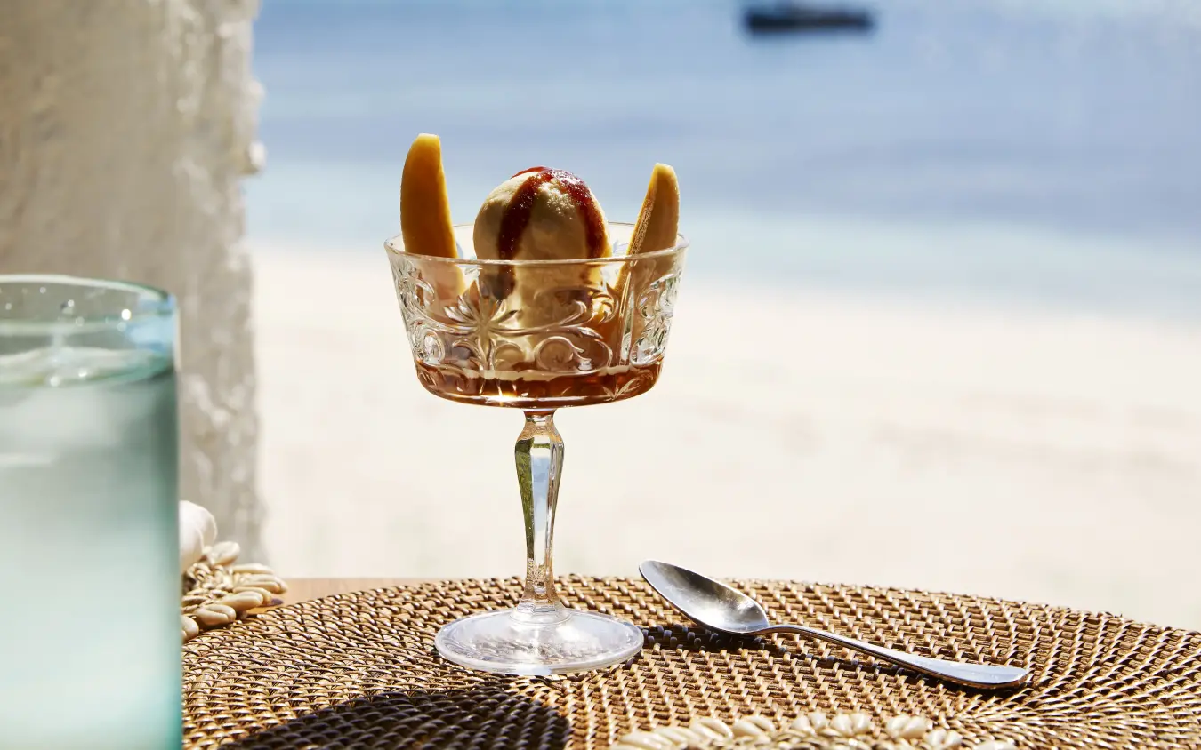 Cocktail with bread in ornate glass on beach table overlooking ocean, Laba Fanjove, Zanzibar & Pemba, Tanzania