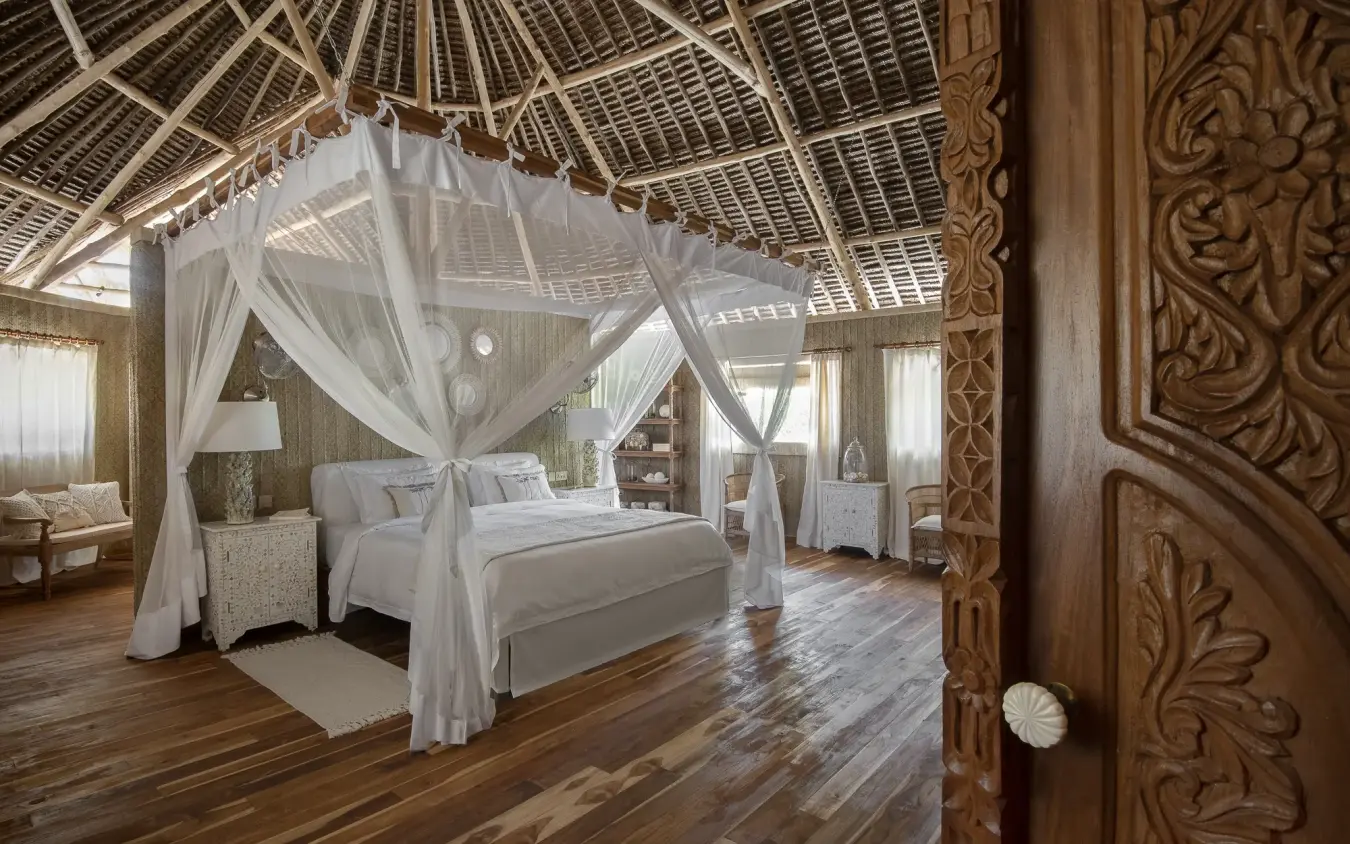 Canopied bed in luxury bedroom with wooden carved door frame, Laba Fanjove, Zanzibar & Pemba, Tanzania