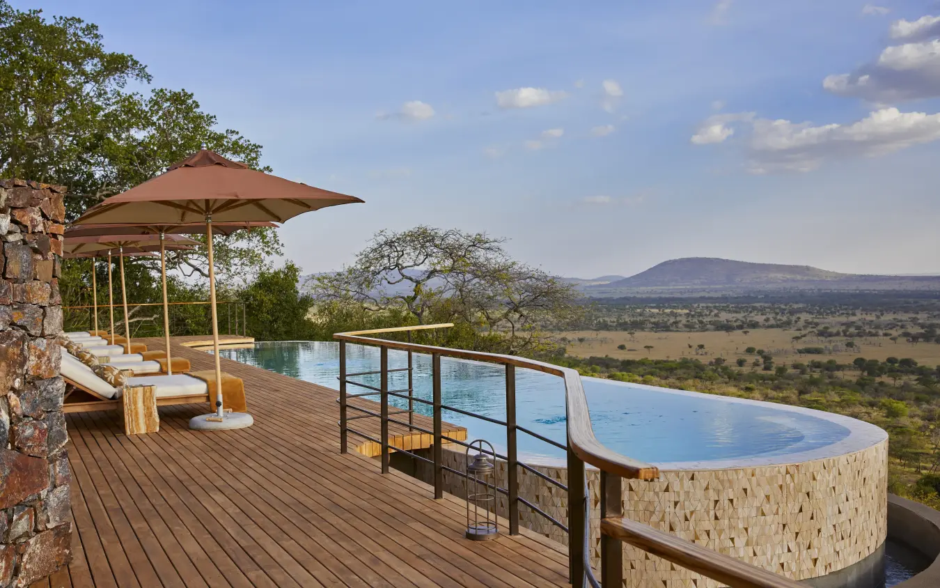 Infinity pool and sun loungers on wooden deck overlooking savanna landscape, Laba Grumeti Art Lodge, Serengeti National Park, Tanzania