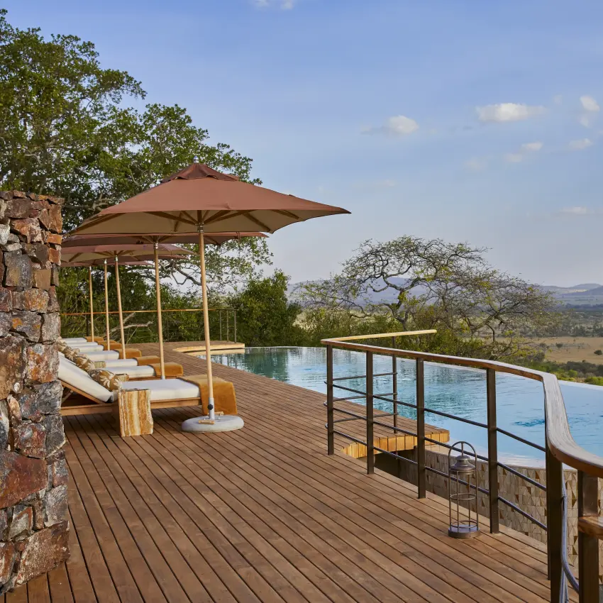 Infinity pool and sun loungers on wooden deck overlooking savanna landscape, Laba Grumeti Art Lodge, Serengeti National Park, Tanzania