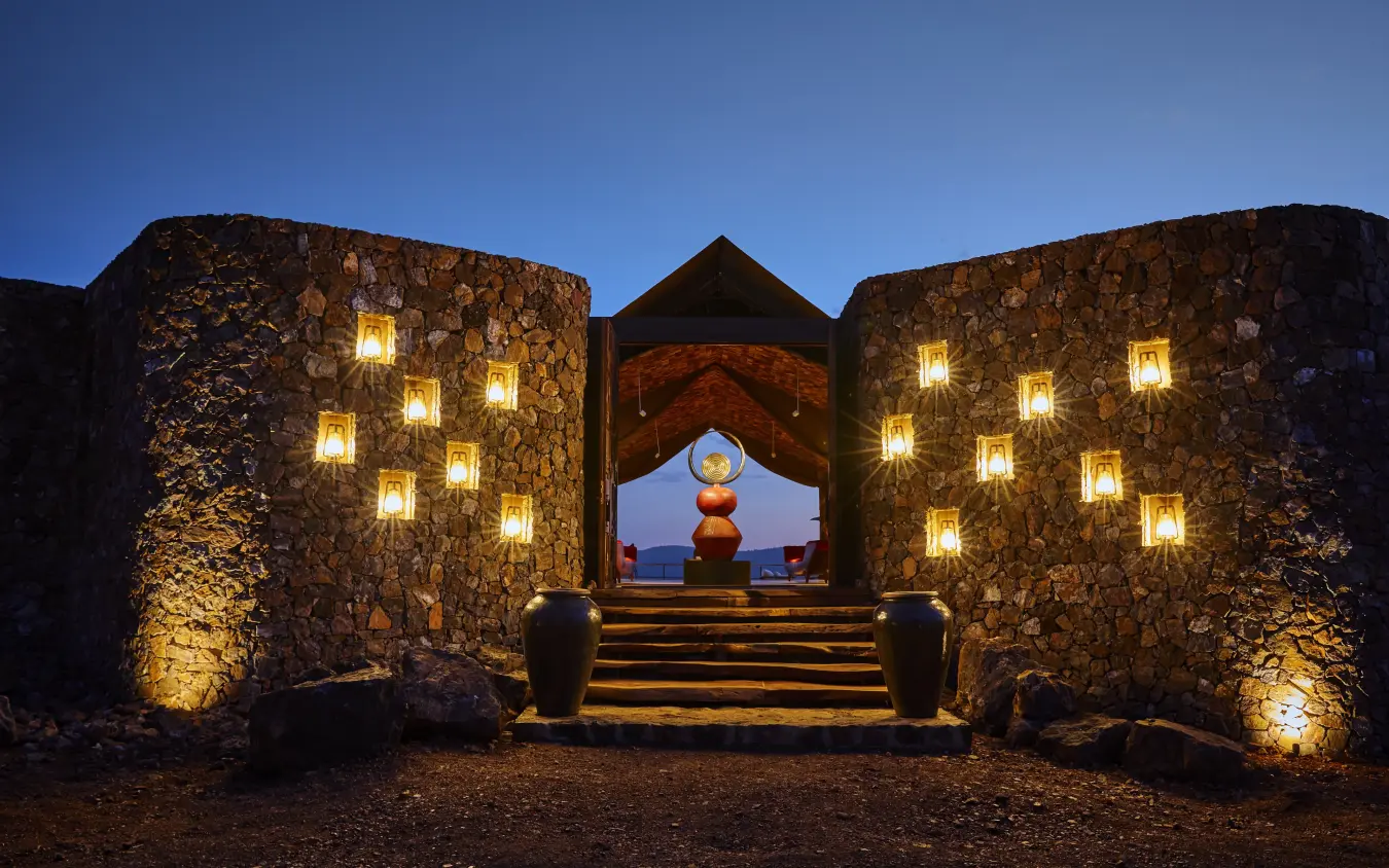 Illuminated stone gateway with coastal view at dusk, Laba Grumeti Art Lodge, Serengeti National Park, Tanzania