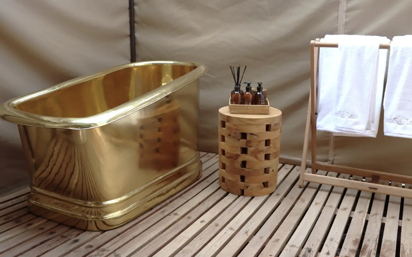 Luxury glamping bathroom with brass bathtub and wooden accessories, Laba Migration Camp, Serengeti National Park, Tanzania