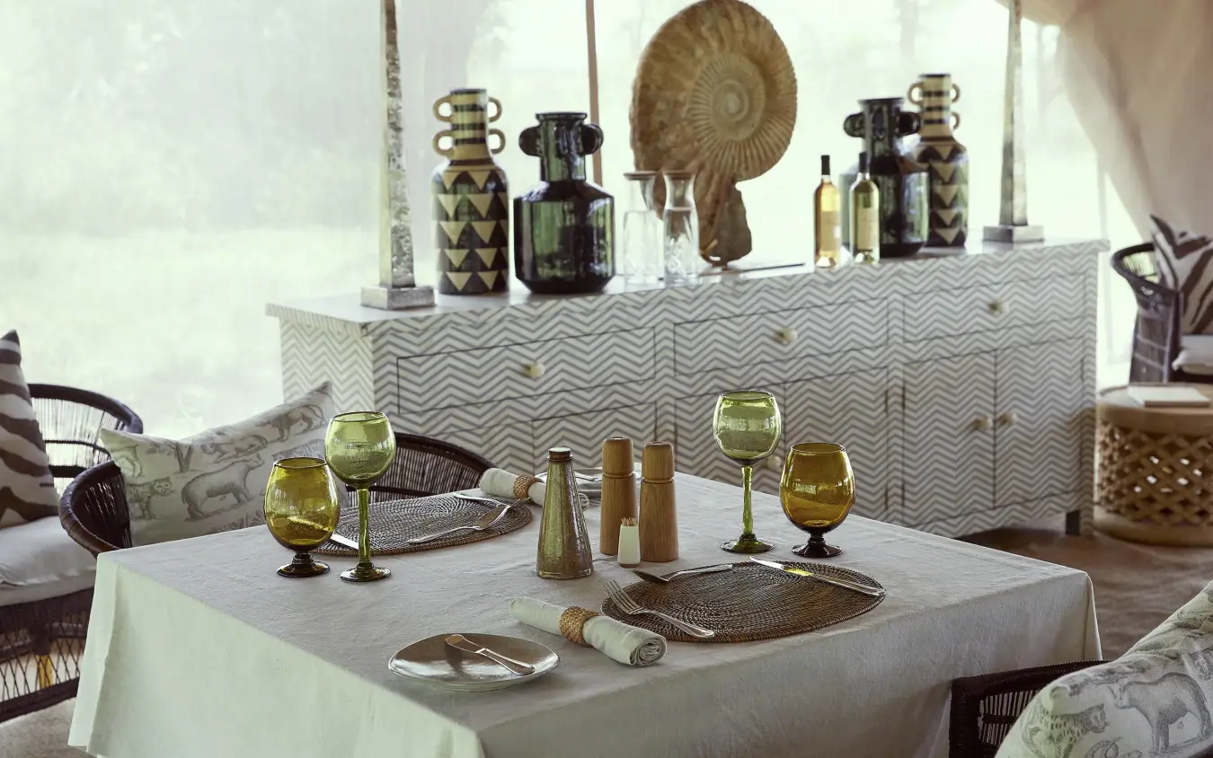 Dining table set for meal with savanna views through windows, Laba Migration Camp, Serengeti National Park, Tanzania