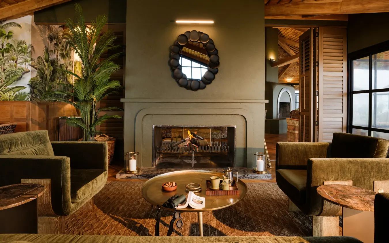 Modern lounge with fireplace, seated guests, and decorative plants indoors, Laba Ngorongoro Lodge, Ngorongoro Crater, Tanzania