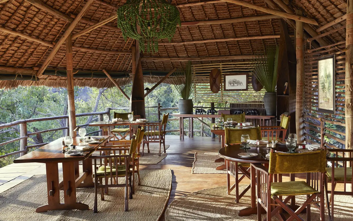 Open-sided dining pavilion with wooden furniture and thatch roof overlooking forest, Laba Siwandu, Nyerere National Park, Tanzania