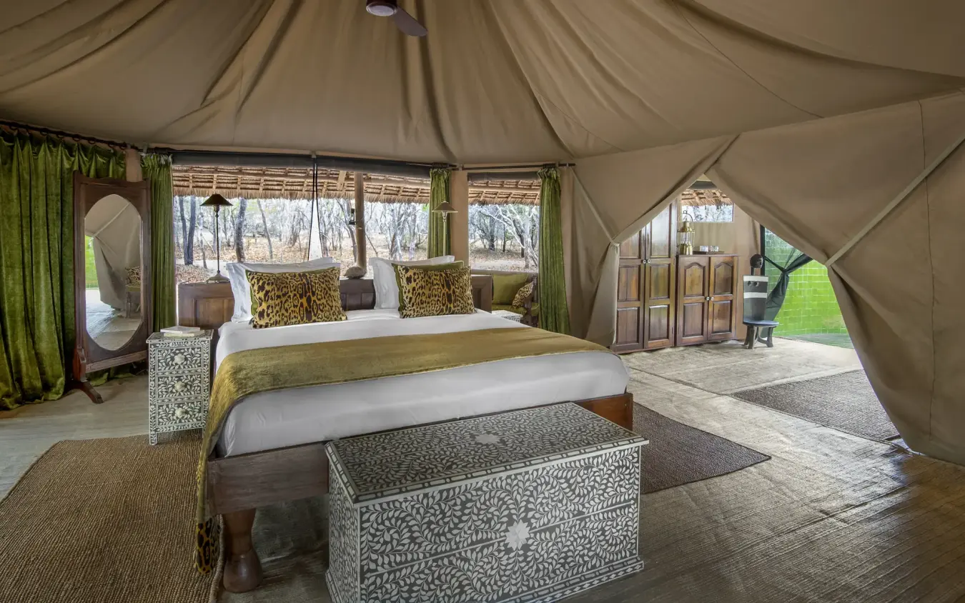 Luxury safari tent bedroom interior with panoramic windows overlooking woodland, Laba Siwandu, Nyerere National Park, Tanzania
