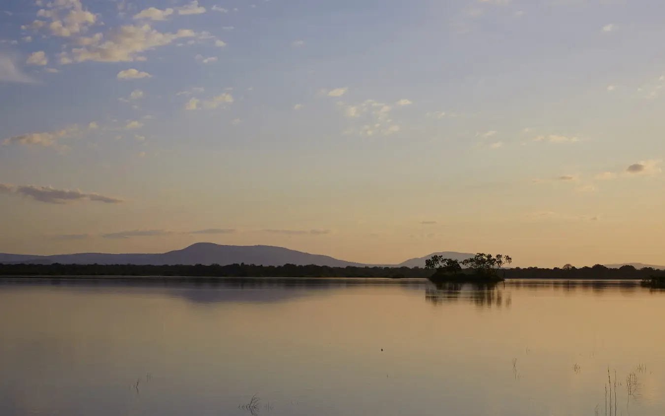 Still lake reflecting mountain and trees at golden hour dusk, Laba Siwandu, Nyerere National Park, Tanzania