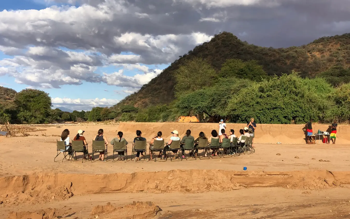 Group seated in circle on sandy riverbed during gathering, Karisia Walking Safaris, Laikipia Highlands, Kenya