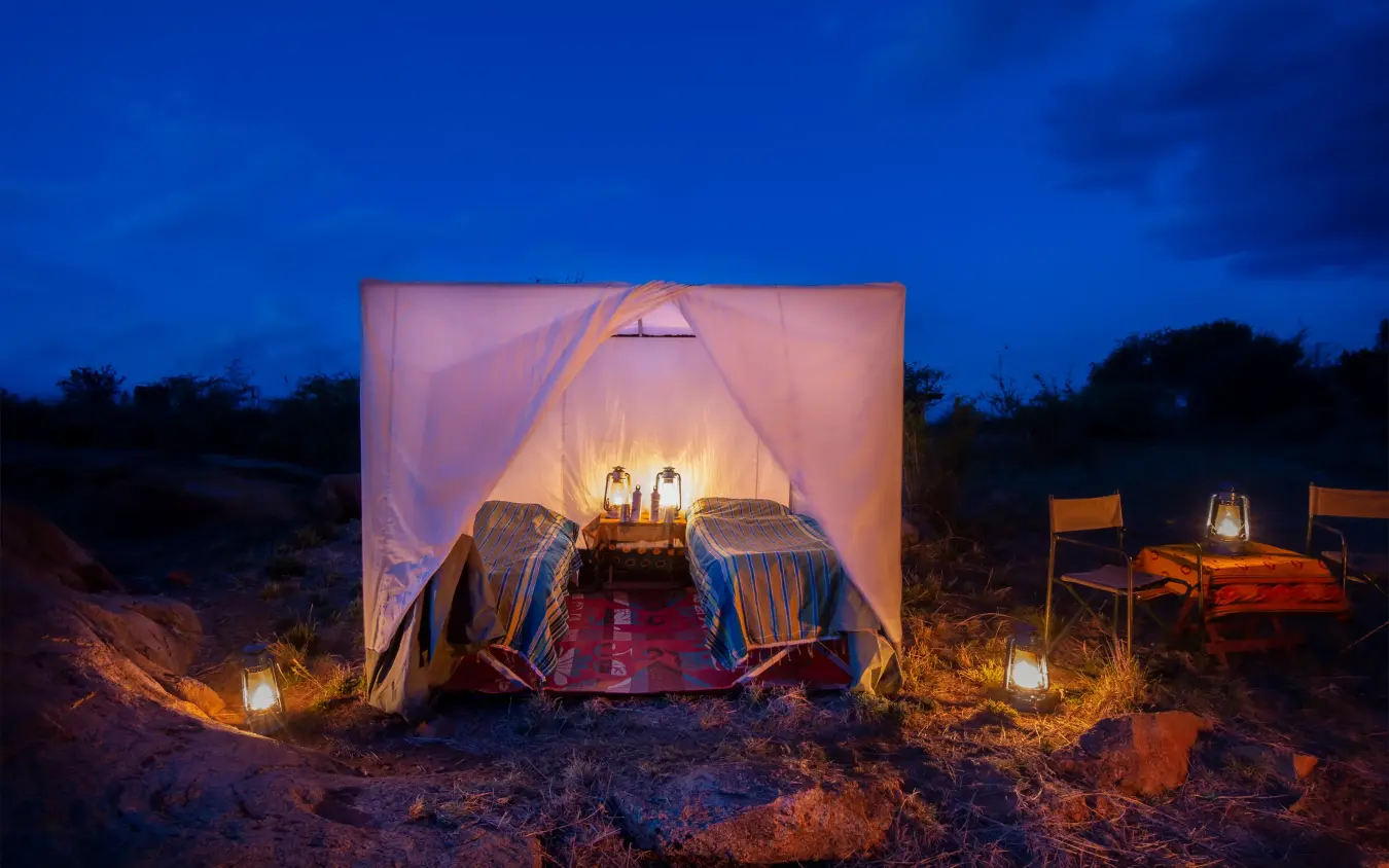 Illuminated canvas tent camp at dusk in wilderness, Laikipia Wilderness, Laikipia Highlands, Kenya