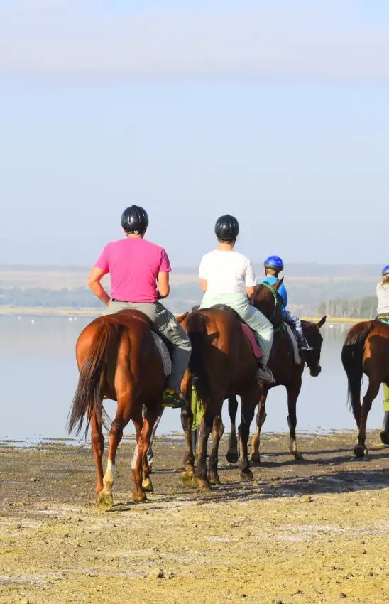 Horseback riders on beach with water and landscape view behind, Lake Elmenteita Serena Camp, Rift Valley Lakes, Kenya