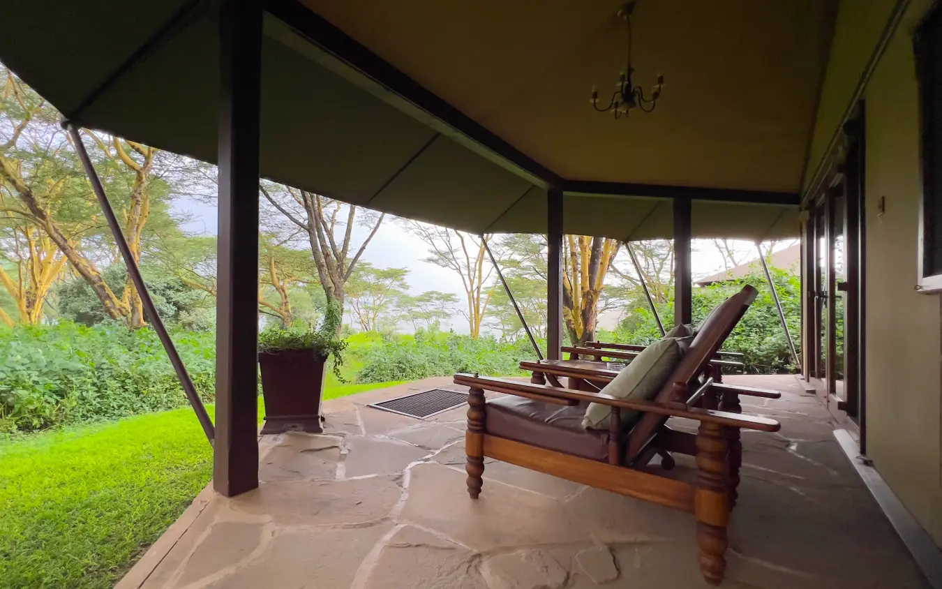 Covered patio with loungers overlooking manicured lawn and woodland, Lake Elmenteita Serena Camp, Rift Valley Lakes, Kenya