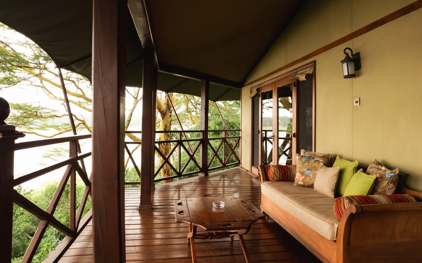 Wooden deck with daybed overlooking treetops and savanna landscape, Lake Elmenteita Serena Camp, Rift Valley Lakes, Kenya