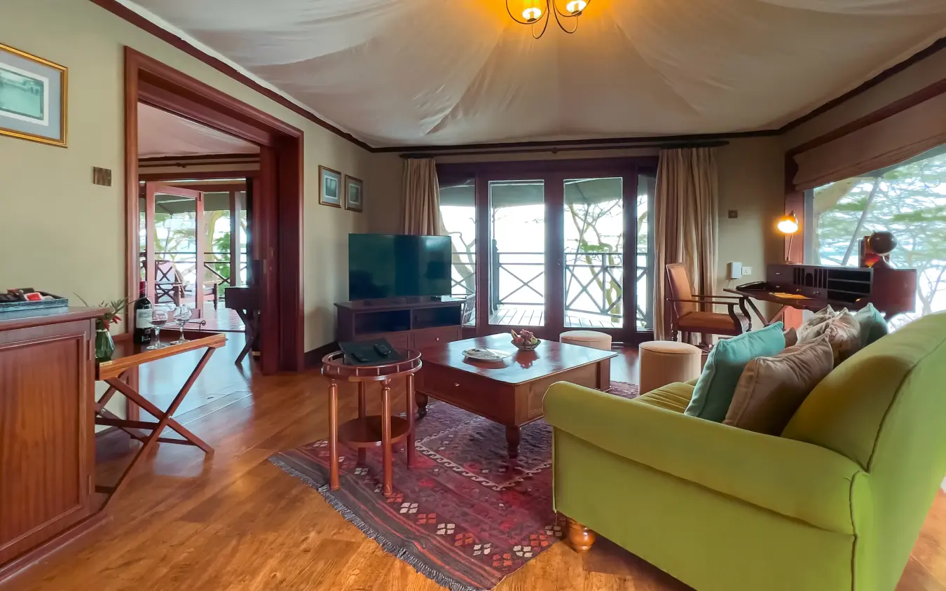 Luxury lodge suite interior with green sofa and balcony overlooking treetops, Lake Elmenteita Serena Camp, Rift Valley Lakes, Kenya