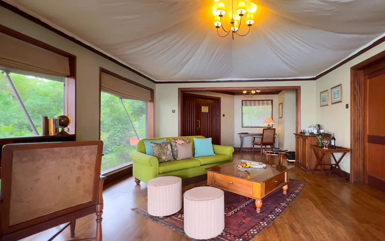 Spacious safari lodge interior with lime green sofa and large windows overlooking woodland, Lake Elmenteita Serena Camp, Rift Valley Lakes, Kenya