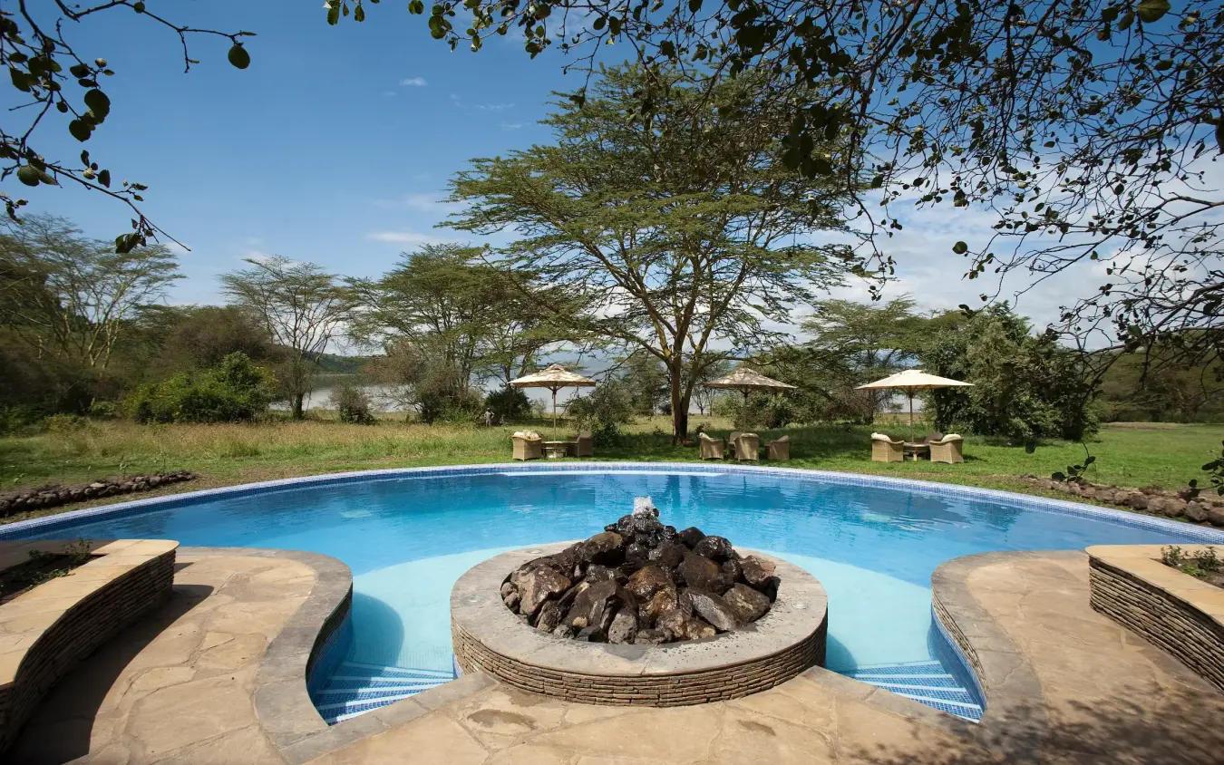 Circular swimming pool with central fire pit surrounded by acacia trees, Lake Elmenteita Serena Camp, Rift Valley Lakes, Kenya