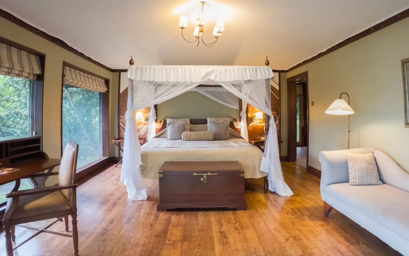 Canopy bed in luxury bedroom suite with wooden floors and large windows, Lake Elmenteita Serena Camp, Rift Valley Lakes, Kenya
