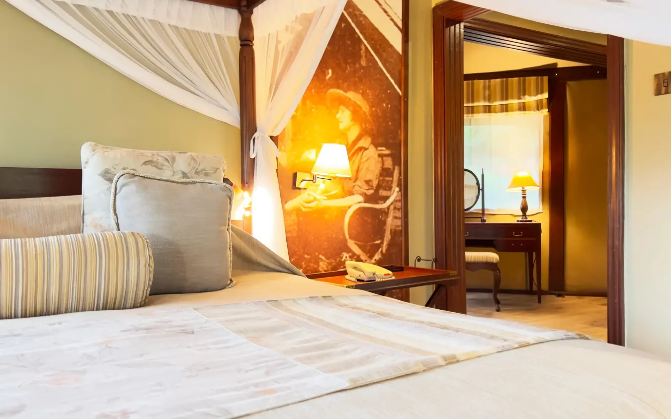Luxury bedroom suite with four-poster bed and adjoining sitting area at dusk, Lake Elmenteita Serena Camp, Rift Valley Lakes, Kenya
