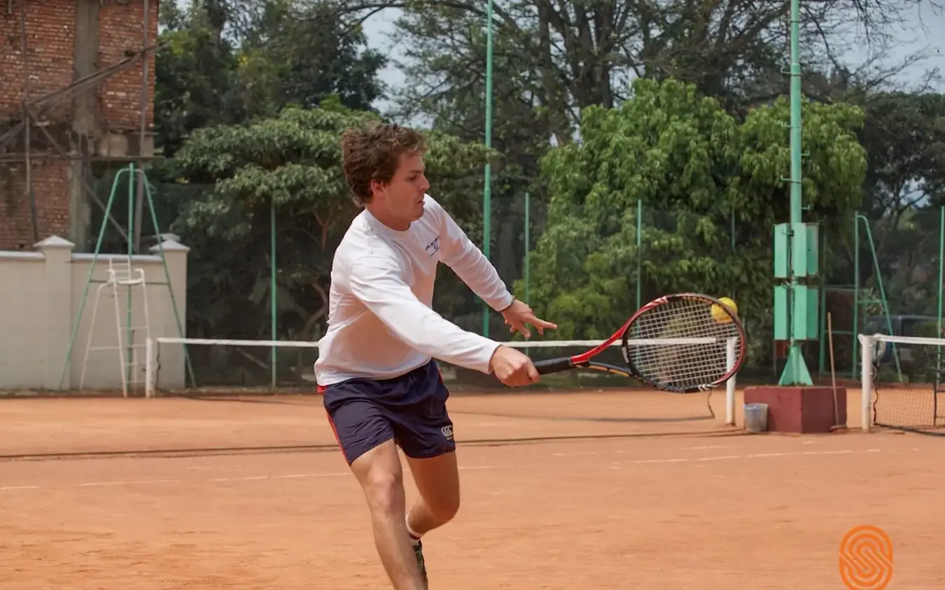 Guest playing tennis on clay court at lodge, Lake Kivu Serena Hotel, Lake Kivu, Rwanda