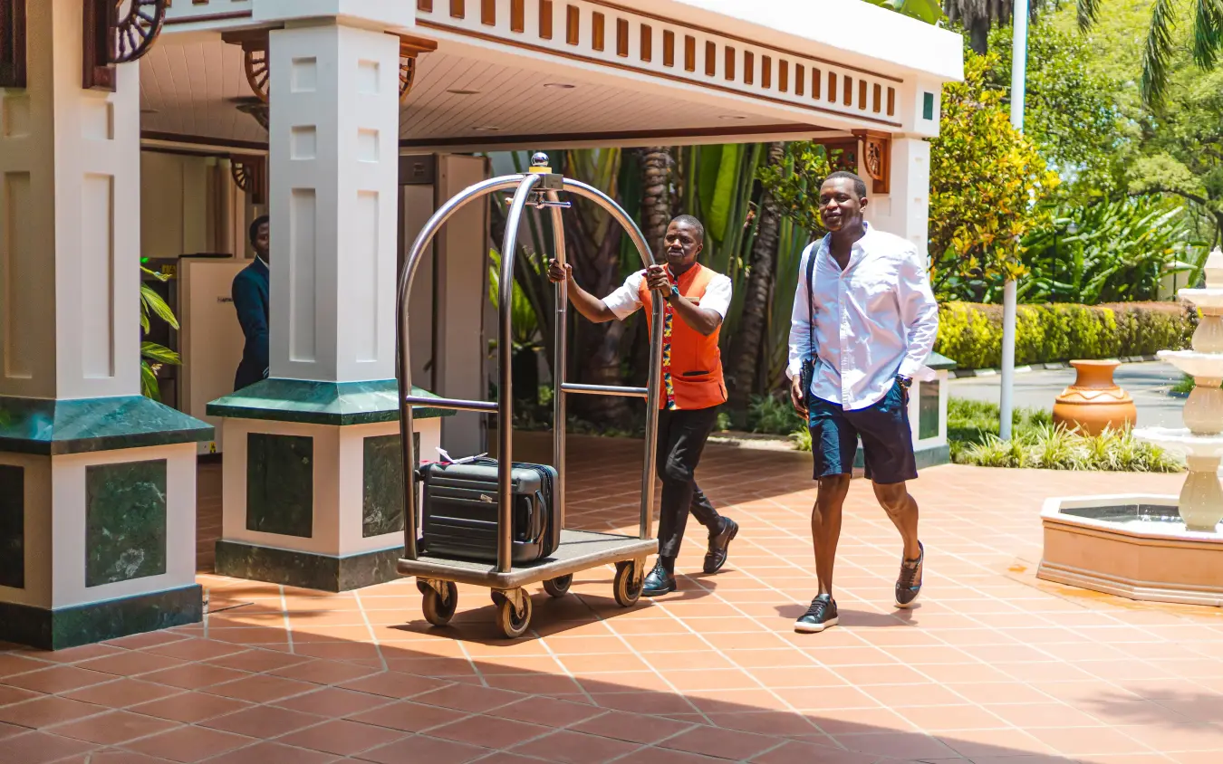 Concierge assisting guests with luggage cart at resort entrance, Lake Kivu Serena Hotel, Lake Kivu, Rwanda