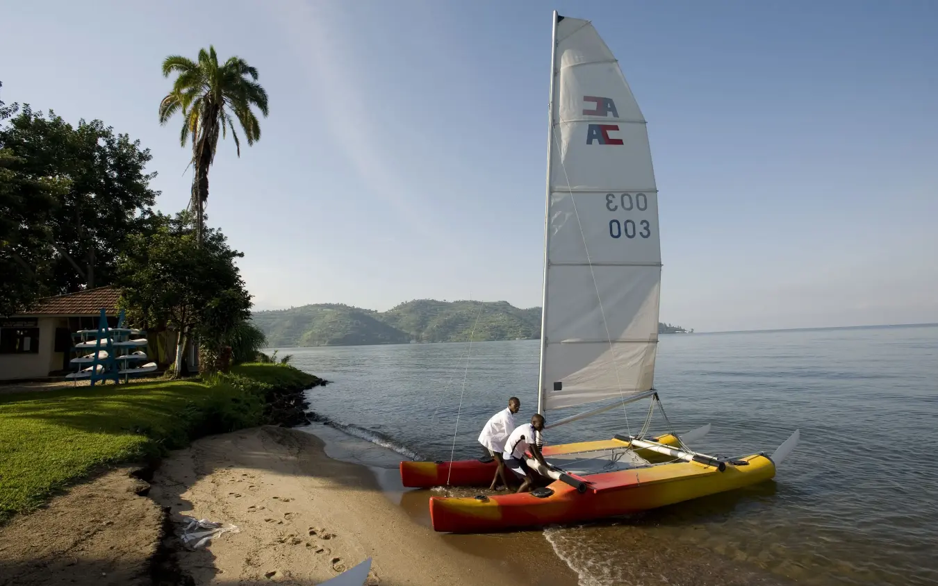 Sailor preparing outrigger canoe with sail on tropical beach, Lake Kivu Serena Hotel, Lake Kivu, Rwanda