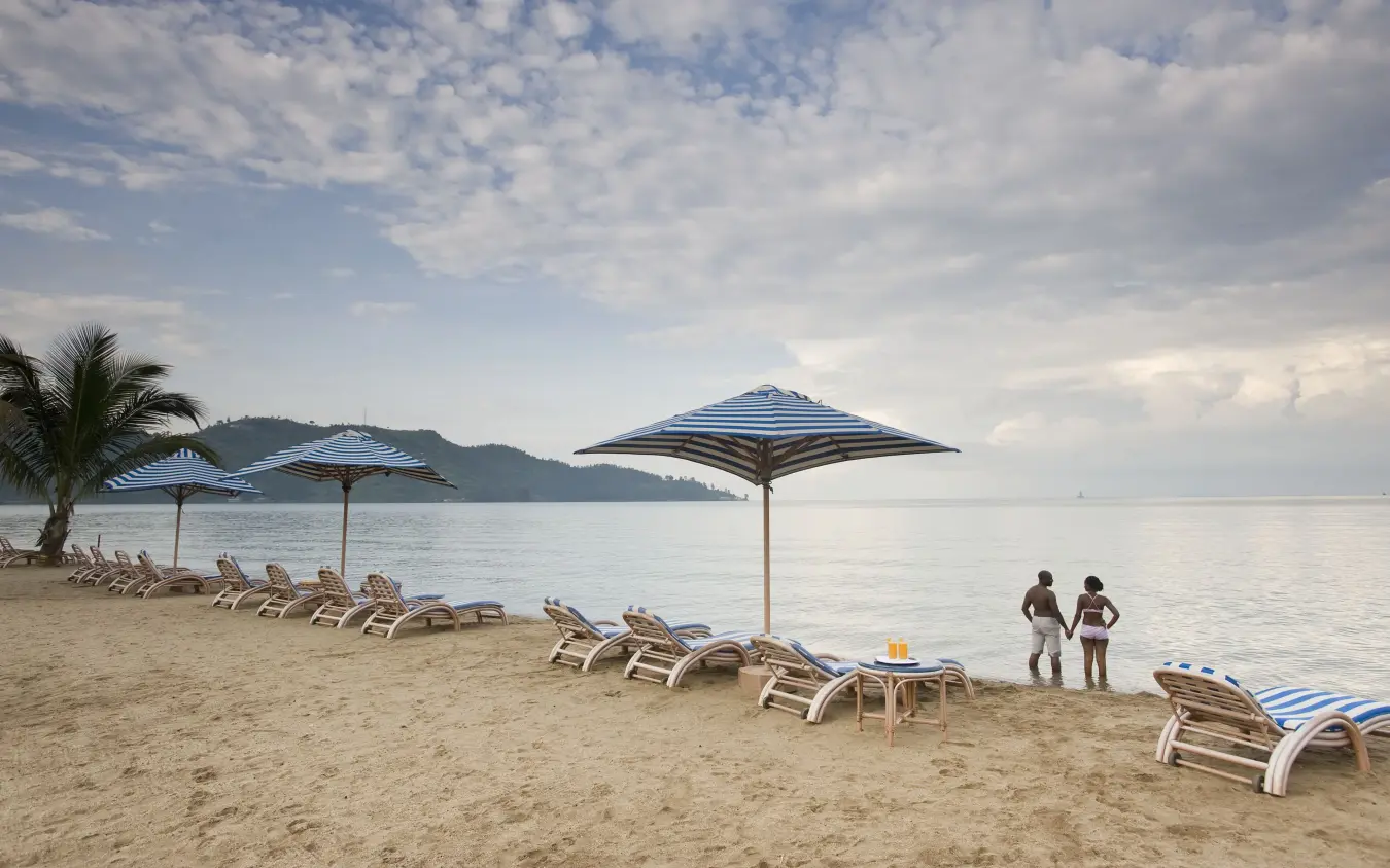 Beach loungers with blue umbrellas overlooking tropical coastline, Lake Kivu Serena Hotel, Lake Kivu, Rwanda