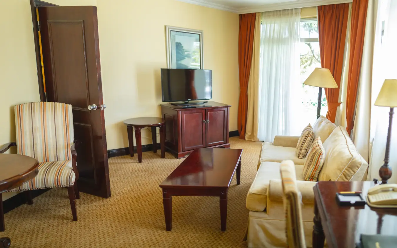 Hotel suite with wood furniture and orange curtains overlooking gardens, Lake Kivu Serena Hotel, Lake Kivu, Rwanda