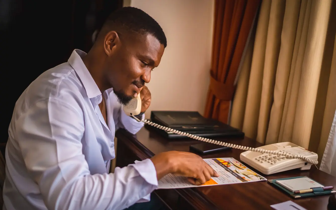 Man in white shirt studying documents at desk with keyboard and notebook, Lake Kivu Serena Hotel, Lake Kivu, Rwanda
