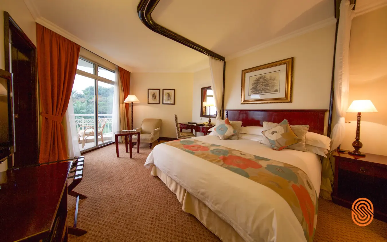 Luxury bedroom suite with four-poster bed and valley views through glass doors, Lake Kivu Serena Hotel, Lake Kivu, Rwanda