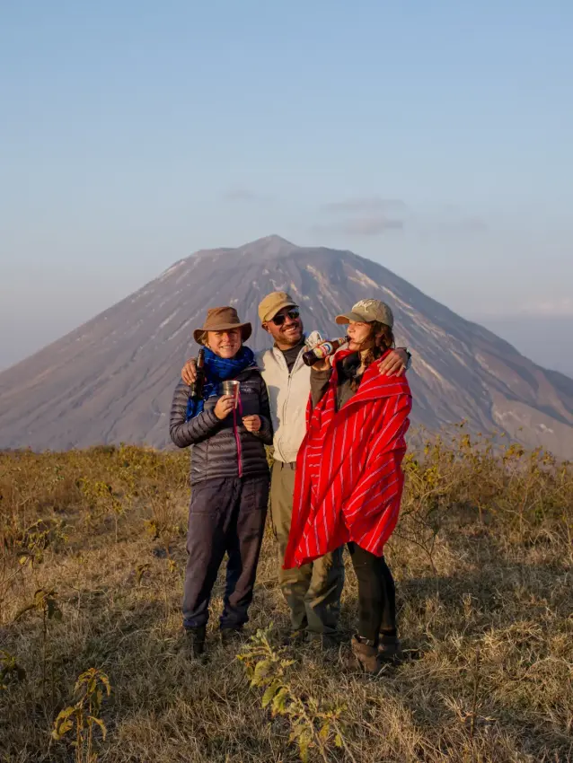 Three guests posing together with mountain backdrop, Lake Natron Camp, Lake Natron, Tanzania
