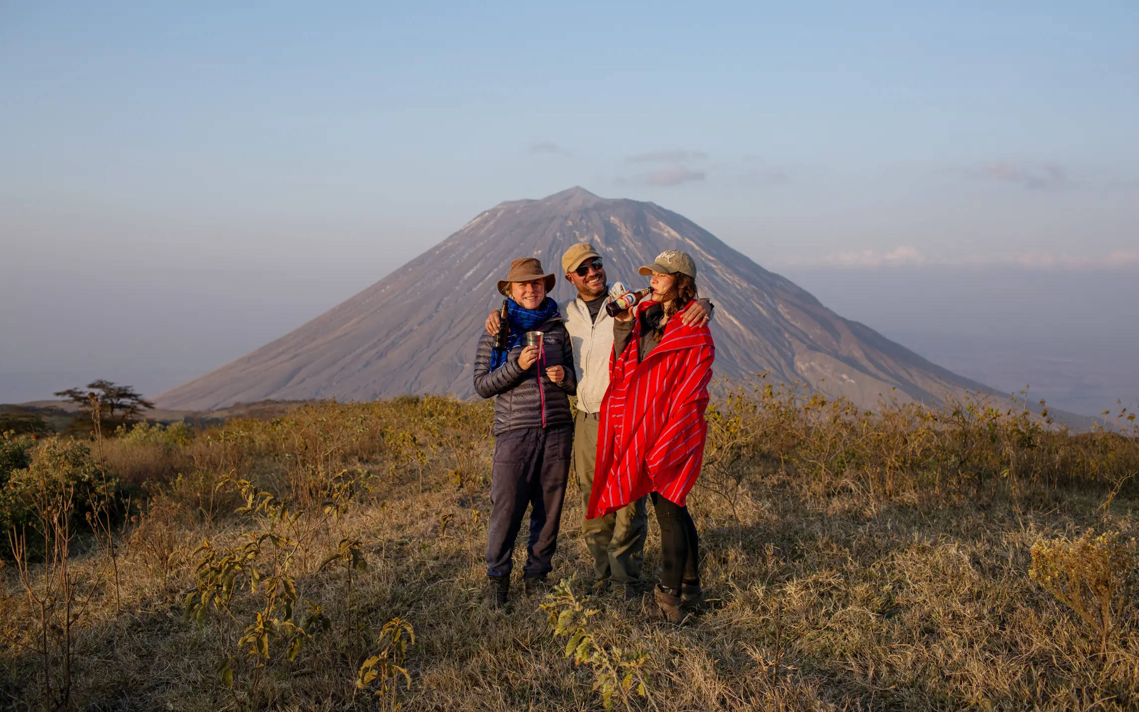 Three guests posing together with mountain backdrop, Lake Natron Camp, Lake Natron, Tanzania