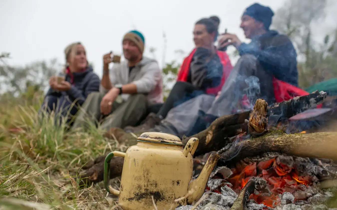 Guests gathered around campfire with kettle brewing, Lake Natron Camp, Lake Natron, Tanzania