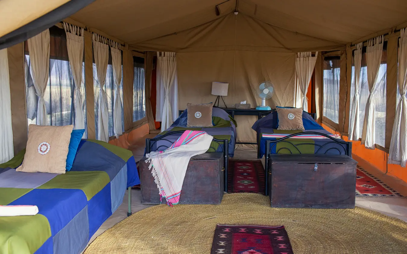 Safari camp bedroom interior with twin beds and colorful bedding, Lake Natron Camp, Lake Natron, Tanzania