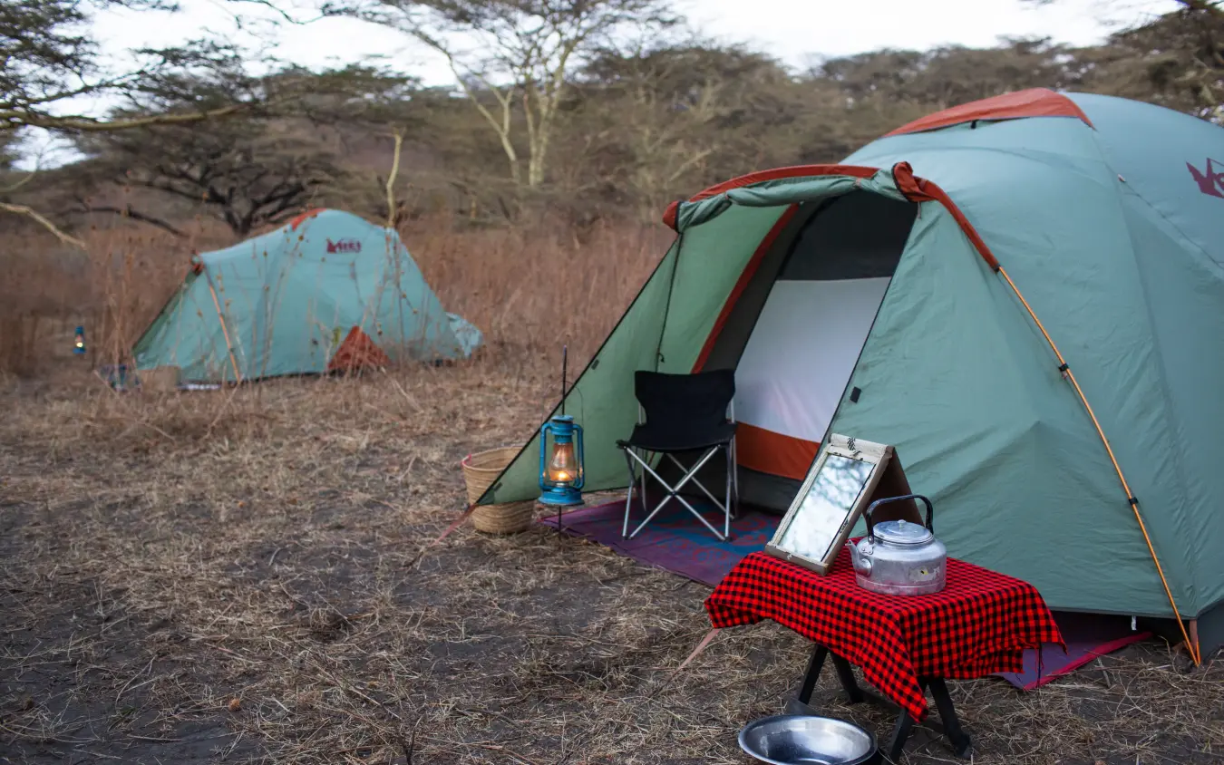 Camping tents and setup in arid landscape with sparse trees, Lake Natron Camp, Lake Natron, Tanzania