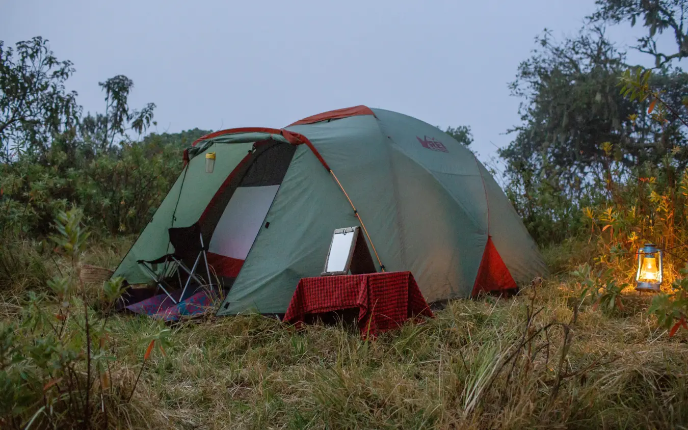 Green dome tent with red accents in grassland at dusk, Lake Natron Camp, Lake Natron, Tanzania