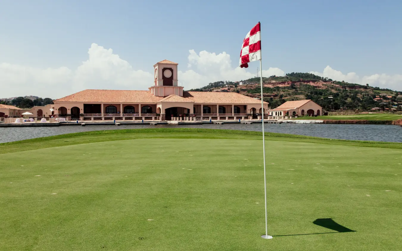 Golf course with clubhouse and Peruvian flag by water, Lake Victoria Serena Golf Resort & Spa, Entebbe and Kampala, Uganda
