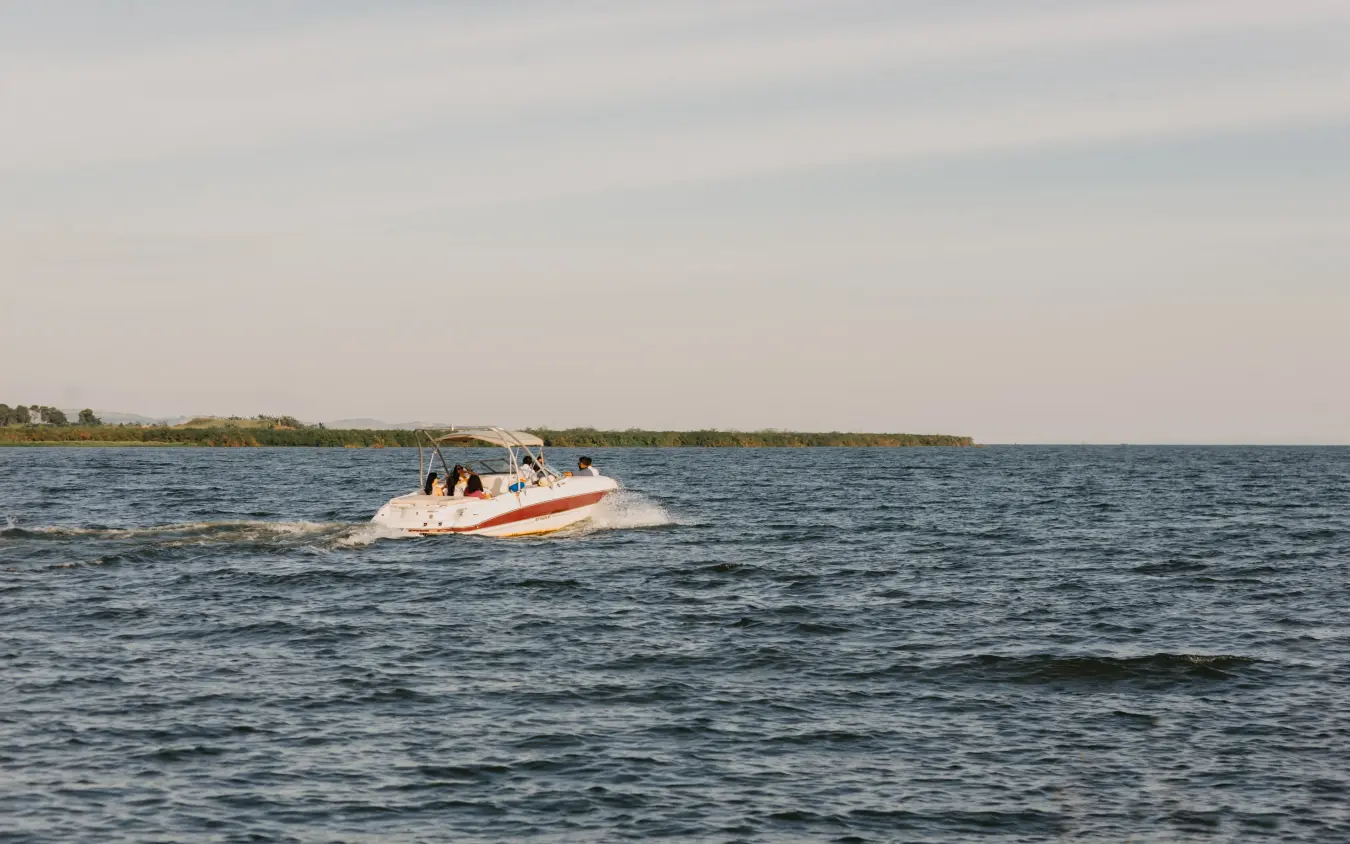 Speed boat with passengers cruising coastal waterway near mangrove shoreline, Lake Victoria Serena Golf Resort & Spa, Entebbe and Kampala, Uganda