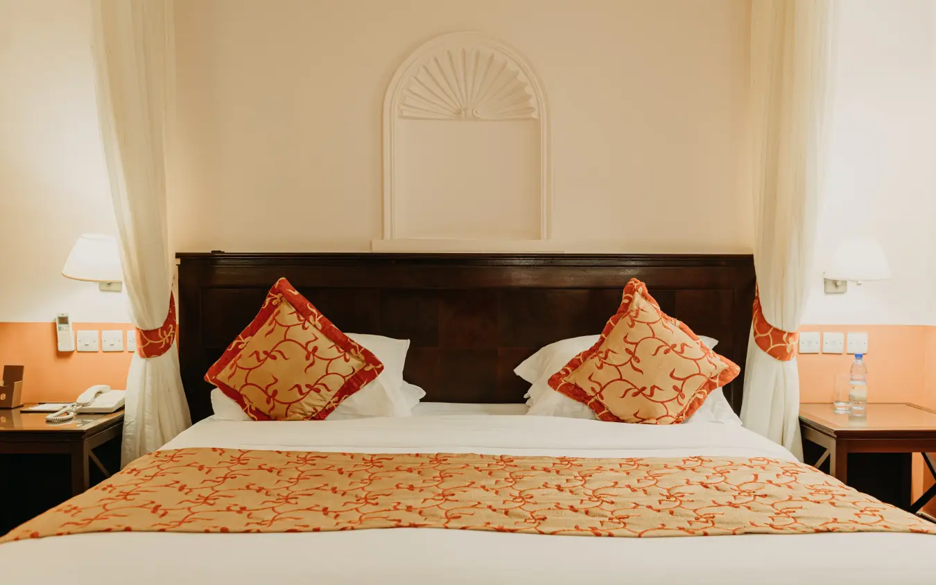 Luxury bedroom with dark wood bed frame and orange patterned bedding, Lake Victoria Serena Golf Resort & Spa, Entebbe and Kampala, Uganda