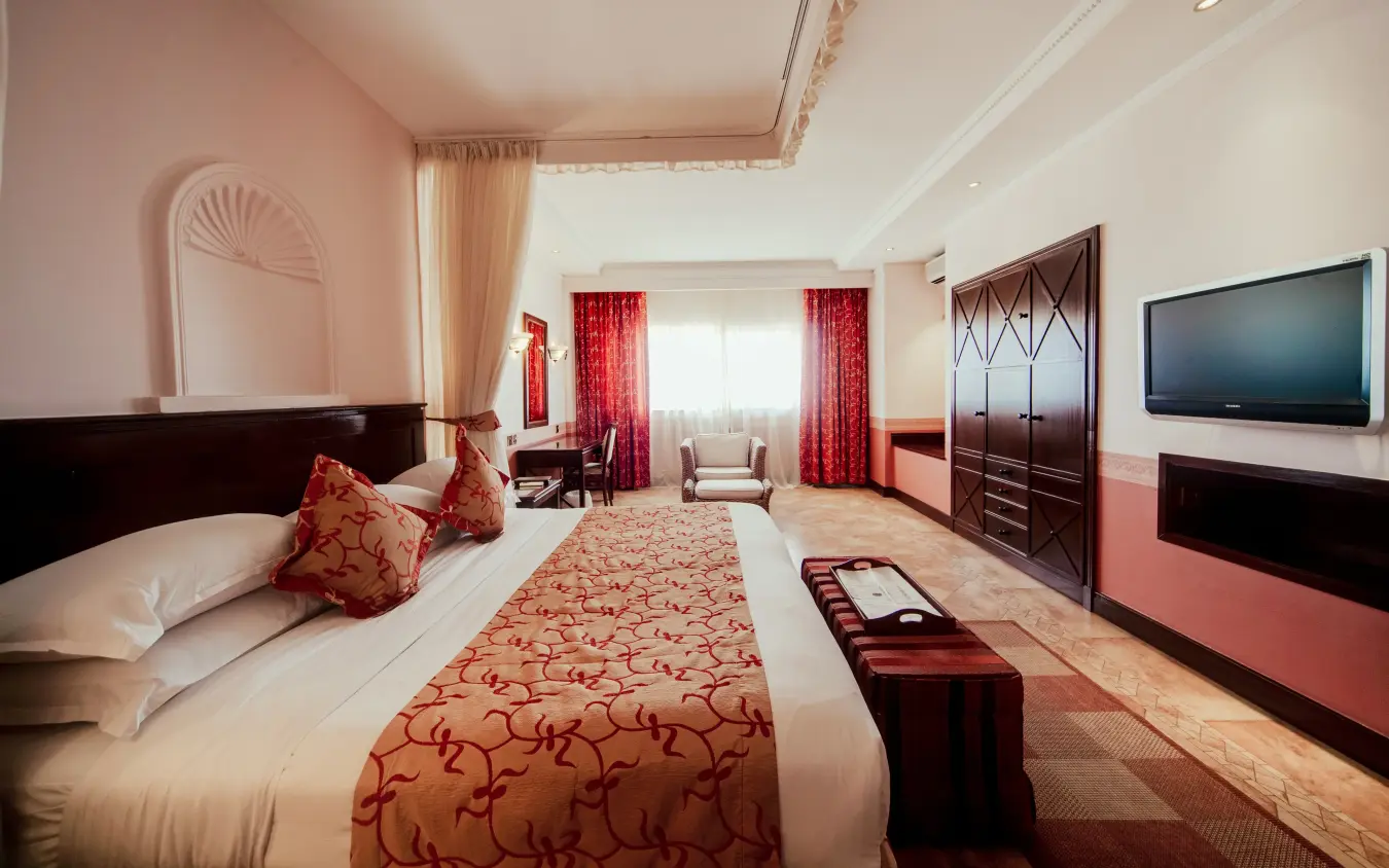 Luxury hotel bedroom with red and gold accents and flat-screen television, Lake Victoria Serena Golf Resort & Spa, Entebbe and Kampala, Uganda