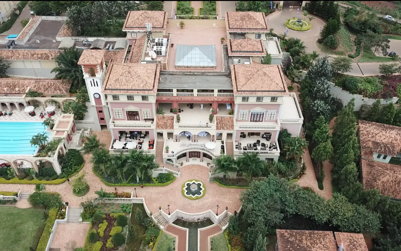 Aerial view of pink colonial-style mansion with terracotta roofs and manicured gardens, Lake Victoria Serena Golf Resort & Spa, Entebbe and Kampala, Uganda