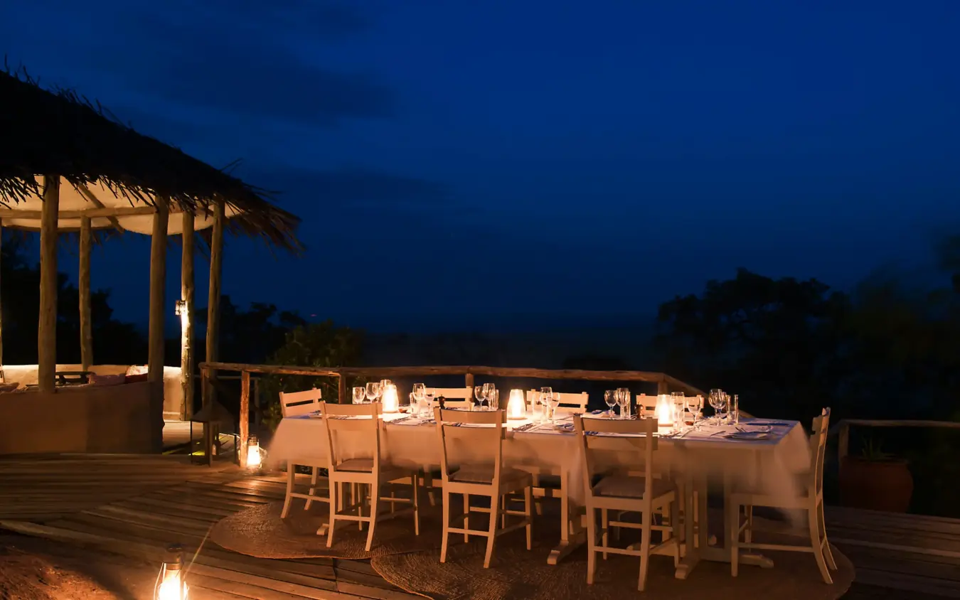 Outdoor dining setup on wooden deck at dusk, Lamai Serengeti, Serengeti National Park, Tanzania
