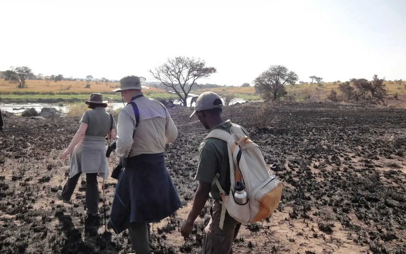 Guests walking across rocky terrain toward water, Serian Serengeti Lamai, Serengeti National Park, Tanzania